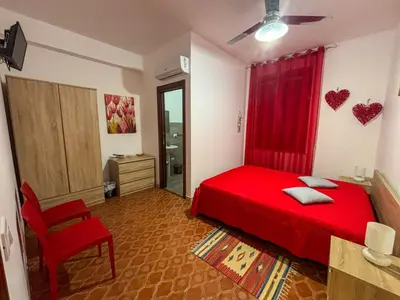 a bedroom with a red bed and a red curtain at Alle Vigne Affittacamere in Alcamo