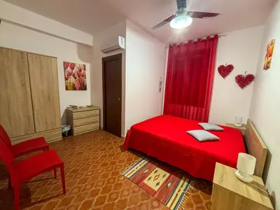 a bedroom with a red bed and a red curtain at Alle Vigne Affittacamere in Alcamo