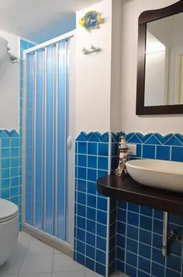 a bathroom with blue tiled walls and a sink at Villa Hibisco in San Vito lo Capo