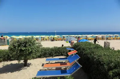 a group of beach chairs and umbrellas on the beach at Villa Hibisco in San Vito lo Capo