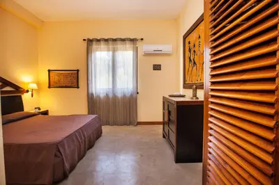 a bedroom with a bed and a dresser and a window at Villa Sole in San Vito lo Capo