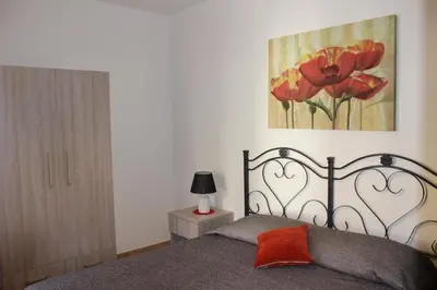 a bedroom with a bed and a painting of flowers at Camere da Mariolina in Macari