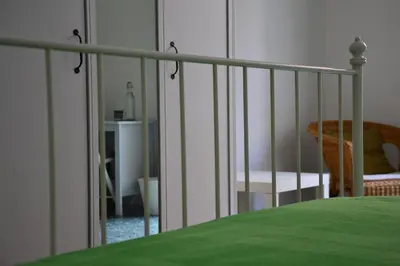 a white bed with a green blanket and a chair at il lapino in Palermo