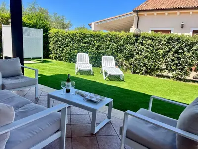 a patio with two chairs and a table with a bottle of wine at Villa Camelie in Campofelice di Roccella