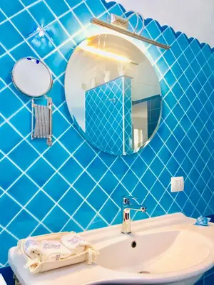 a blue tiled bathroom with a sink and a mirror at Villa Camelie in Campofelice di Roccella