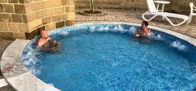 two men are sitting in a swimming pool at Villa Camelie in Campofelice di Roccella
