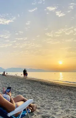 two people sitting in chairs on the beach at sunset at Villa Camelie in Campofelice di Roccella