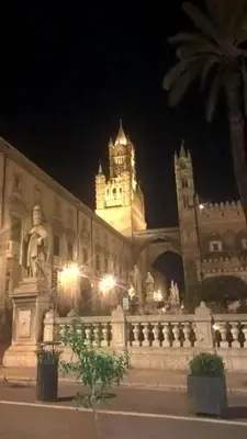 a large building with a clock tower at night at Millimetro in Palermo