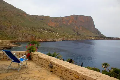 a blue chair sitting on a wall next to the water at Villa Firriato in San Vito lo Capo