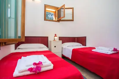 two beds in a room with red sheets and towels at Villa Firriato in San Vito lo Capo
