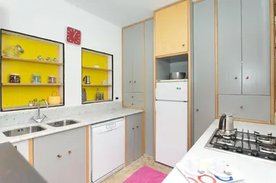 a kitchen with white cabinets and yellow shelves at Villa Firriato in San Vito lo Capo