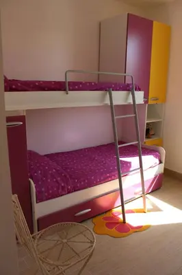 a bedroom with two bunk beds and a chair at Casa Vacanze Roccella Beach in Campofelice di Roccella