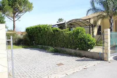 a fence in front of a house with bushes at Casa Vacanze Roccella Beach in Campofelice di Roccella
