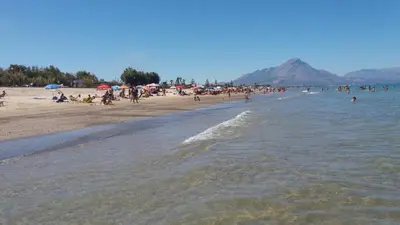a crowd of people on a beach with a mountain in the background at Casa Vacanze Roccella Beach in Campofelice di Roccella