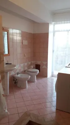 a bathroom with two sinks and a toilet and a window at Casa Timpanella in Partinico
