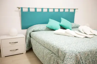 a bedroom with a bed with green and blue pillows at Appartamenti Cala Azzurra in Scopello