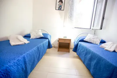 two beds in a room with blue sheets at Appartamenti Cala Azzurra in Scopello