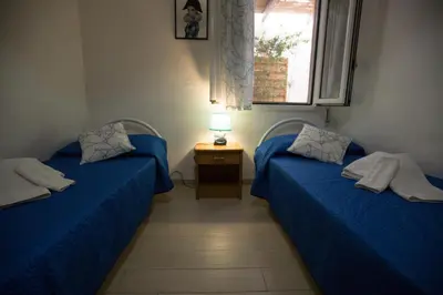 two blue beds in a room with a window at Appartamenti Cala Azzurra in Scopello