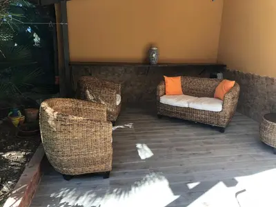 two wicker chairs and a couch on a patio at Appartamenti Cala Azzurra in Scopello