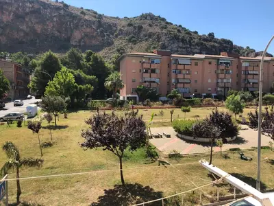 a park in front of a building with a mountain at Appartamento Vacanza Luna in Partinico
