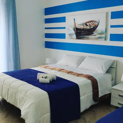 a bedroom with a bed with a blue and white wall at White in Castellammare del Golfo