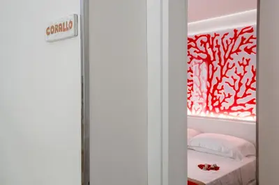 a room with a bed with a red wall at Il Mare Dentro Rooms in San Vito lo Capo