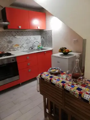 a kitchen with red cabinets and a table in it at Appartamenti La Stella in Castellammare del Golfo