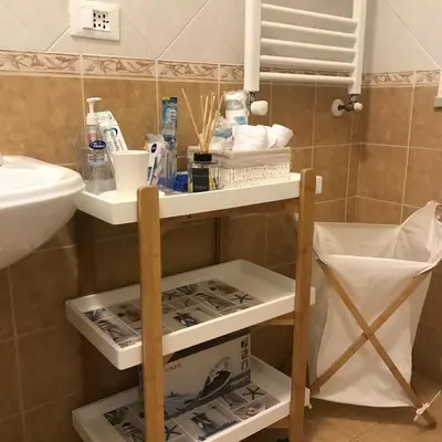 a bathroom with a sink and a shelf withitems at Holiday & House - Imparato Vacanze Prestige Mondello in Mondello