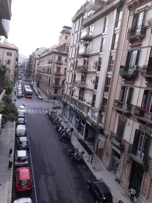 a city street with cars parked next to tall buildings at Zammù in Palermo