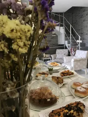 a table with plates of pastries and a vase of flowers at Cima Bianca in San Vito lo Capo