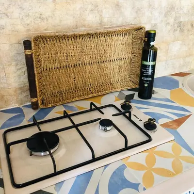 a stove top with a bottle of wine on a counter at Sicilia Vacation in San Vito lo Capo