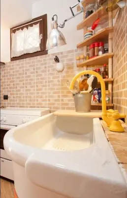 a kitchen with a white sink with a yellow faucet at Case Vacanza Cipriano spacious apartment and cosy studio monolocale in Torretta