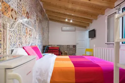 a bedroom with a bed with a colorful blanket at Nonna Anna Rooms in Palermo