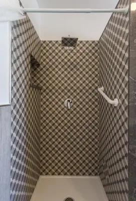 a bathroom with a shower with a tiled wall at Nonna Anna Rooms in Palermo