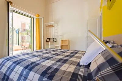 a bedroom with a bed with a blue and white checkered blanket at Nonna Anna Rooms in Palermo