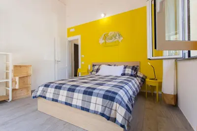 a bedroom with a bed and a yellow wall at Nonna Anna Rooms in Palermo