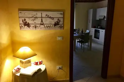 a room with a table with a lamp and a kitchen at Al Duomo in Partinico