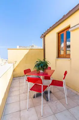 a patio with red chairs and a table on a roof at Casa Turano in Castellammare del Golfo