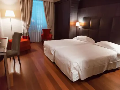 a bedroom with a large white bed and a red chair at Hotel Porta Felice & Spa in Palermo