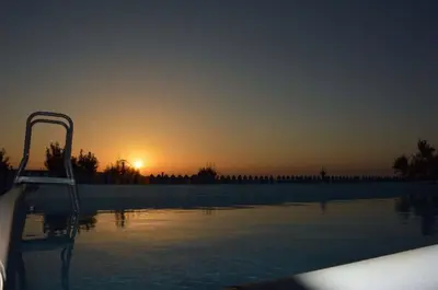 a swimming pool with the sunset in the background at Baglio Del Sole in San Vito lo Capo