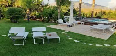 a group of chairs and a table and a pool at Isola del sole, Appartamenti con piscina in Balestrate