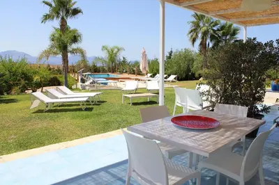 a patio with a table and chairs and a pool at Isola del sole, Appartamenti con piscina in Balestrate