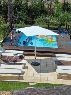 a woman and a child laying in a pool with an umbrella at Isola del sole, Appartamenti con piscina in Balestrate