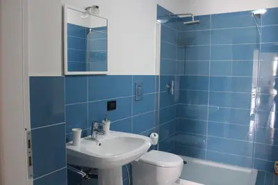 a blue tiled bathroom with a sink and a toilet at Isola del sole, Appartamenti con piscina in Balestrate