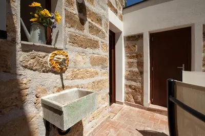 a stone wall with a cement sink on the side of a building at Le Alcove in Cinisi