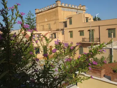 a building with purple flowers in front of it at Tenuta Sperlinga - Il Campanile in Santa Flavia