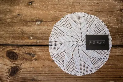 a white crochet hat with a sign on a wooden table at Settegrana in Cinisi