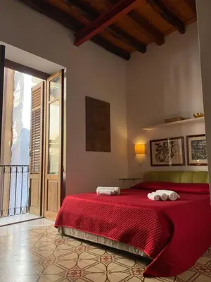 a bedroom with a red bed with two towels on it at 3Sisters Apartments in Palermo