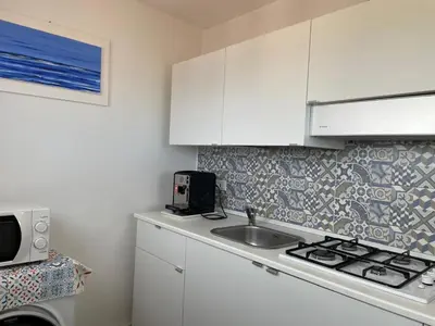 a kitchen with white cabinets and a sink and a stove at Suite de la Sicilienne in Castellammare del Golfo