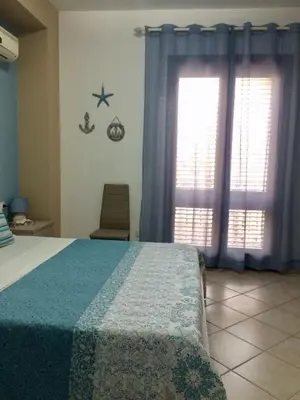 a bedroom with a bed with blue curtains and a window at Ca&Sa Sweet Holiday in Cinisi